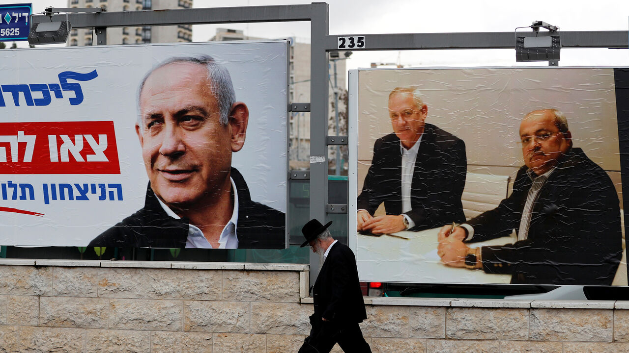 An ultra-Orthodox Jewish man walks next to Likud party election campaign banners, one depicting party leader Israeli Prime Minister Benjamin Netanyahu and the other depicting Benny Gantz, head of Blue and White party and Ahmad Tibi, co-leader of the Joint List, an Arab party, in Jerusalem February 20, 2020. Picture taken February 20, 2020. REUTERS/Ammar Awad - RC297F9OEC8G