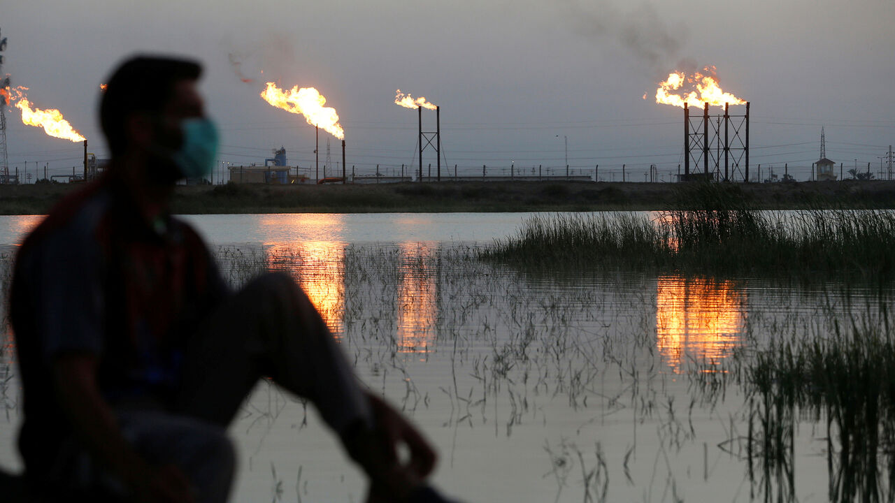 Flames emerge from flare stacks at Nahr Bin Umar oil field, as a man is seen wearing a protective face mask, following the outbreak of the coronavirus, north of Basra, Iraq March 9, 2020. REUTERS/Essam Al-Sudani - RC2IGF9A1IYO