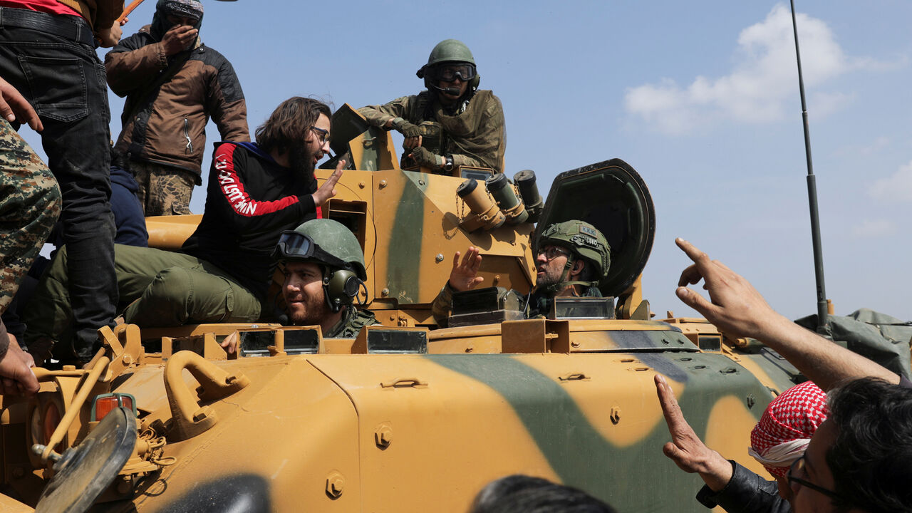 A Turkish soldier gestures as people stand on a military vehicle during a protest against the agreement on joint Russian and Turkish patrols, at M4 highway in Idlib province, Syria, March 15, 2020. REUTERS/Khalil Ashawi - RC2EKF9R77N5
