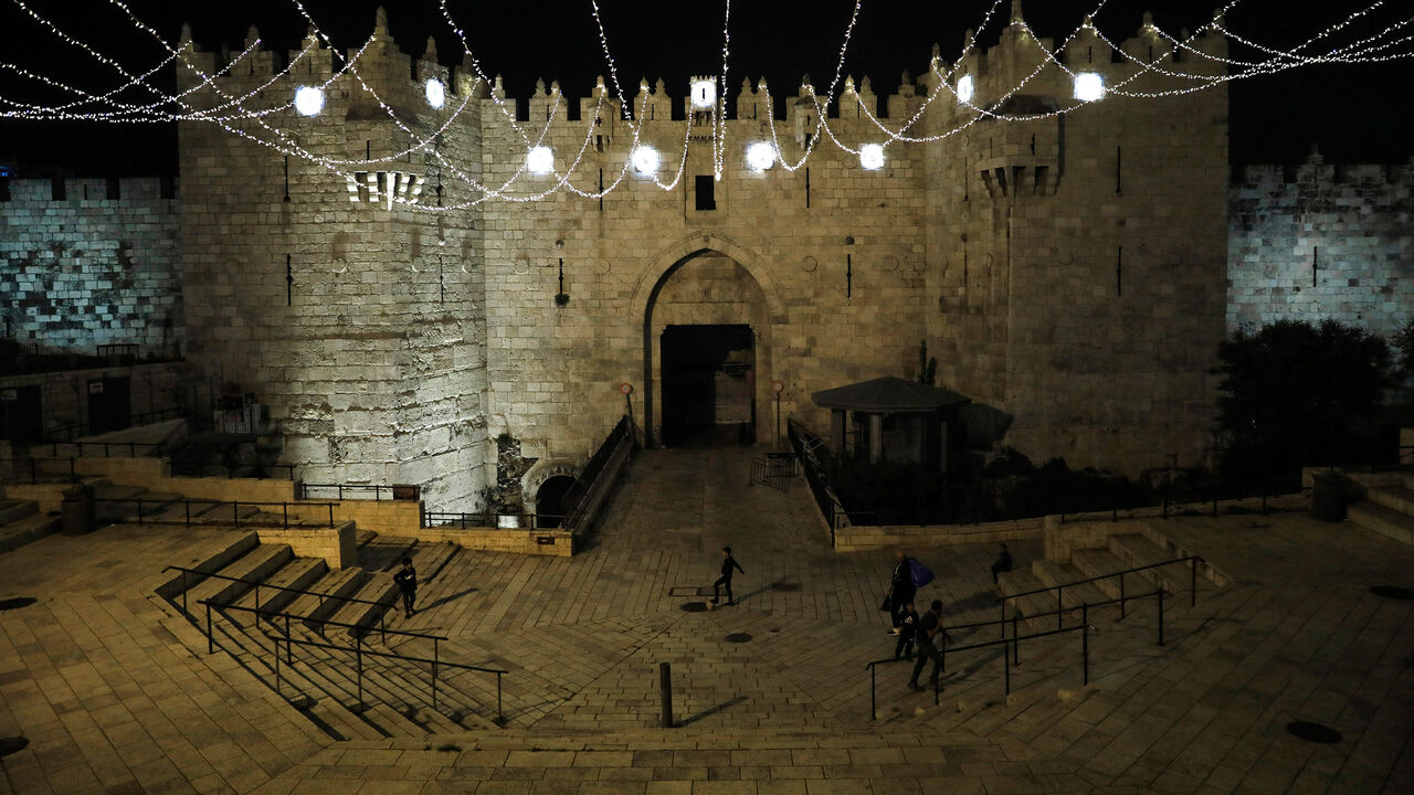 People walk under lights decorating the Damascus Gate in Jerusalem's Old City on April 19, 2020, as Muslims around the world prepare for the holy Muslim month of Ramadan amid the COVID-19 pandemic. (Photo by Ahmad GHARABLI / AFP) (Photo by AHMAD GHARABLI/AFP via Getty Images)