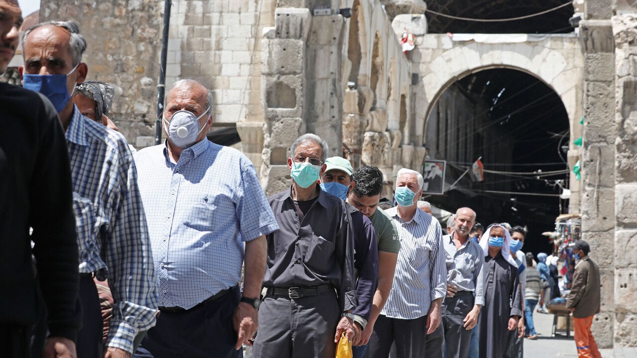 Syrian Muslim men wearing face masks, queue to enter the Umayyad Mosque in Damascus to attend the Friday prayer on May 15, 2020, following the authorities' decision to allow prayers on Fridays in disinfected mosques with strict social distancing and protection measures to limit the spread of the coronavirus COVID-19 pandemic. - President Bashar al-Assad warned earlier this month of a "catastrophe" in war-battered Syria if the easing of lockdown measures against coronavirus is mishandled. (Photo by LOUAI BES