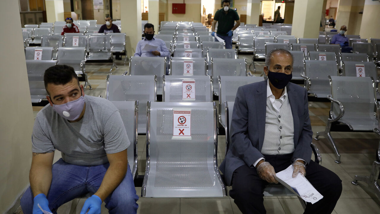 People  wearing protective face masks wait to complete their transactions in the Civil Status Department after Jordan's public sector employees returned gradually to work, two months after they were ordered to stay home as part of a tight lockdown to stem the spread of the coronavirus disease (COVID-19), in Amman, Jordan May 26, 2020. REUTERS/Muhammad Hamed - RC2CWG9G4C2S