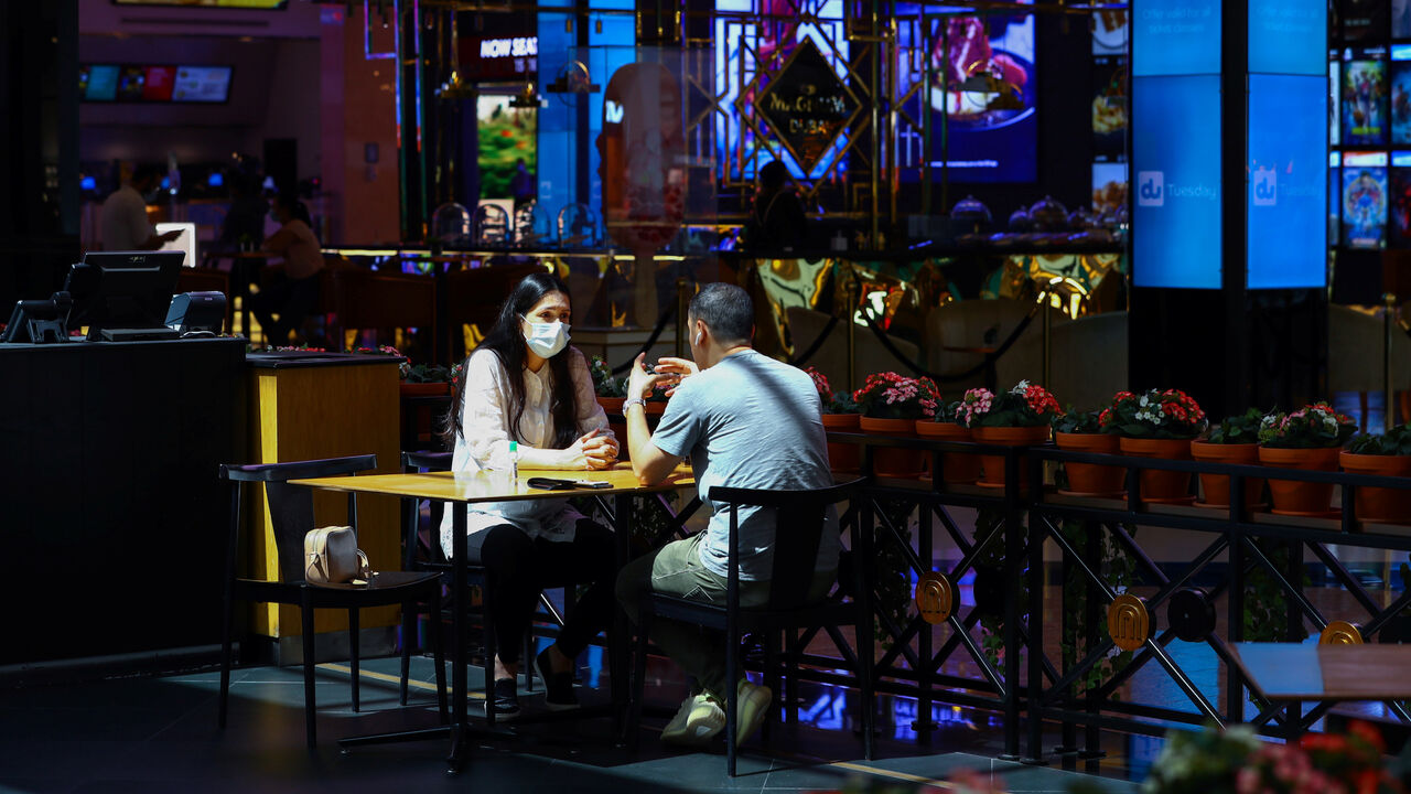 A woman wears a protective face mask as she sits with her friend in a coffee shop during the reopening of malls, following the outbreak of the coronavirus disease (COVID-19), at Mall of the Emirates in Dubai, United Arab Emirates, May 28, 2020. REUTERS/Ahmed Jadallah - RC2SXG92QGHW