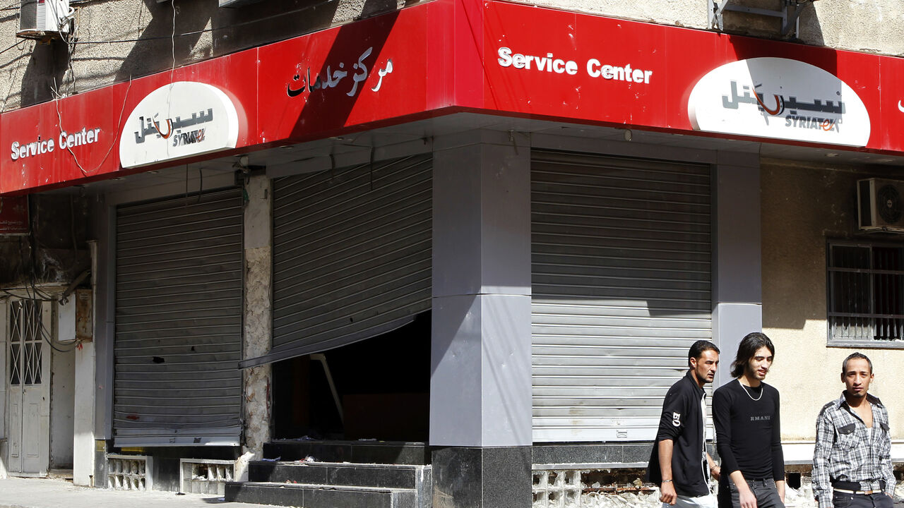 People walk past the looted premises of cellphone company Syriatel, which is owned by Rami Makhlouf, the cousin of Syria's President Bashar al-Assad, in Deraa March 21, 2011. Unrest spread in southern Syria on Monday with hundreds of people demonstrating against the government after five civilians were killed in protests in the city of Deraa over the past four days.REUTERS/Khaled al-Hariri (SYRIA - Tags: POLITICS CIVIL UNREST BUSINESS) - GM1E73M07IA01
