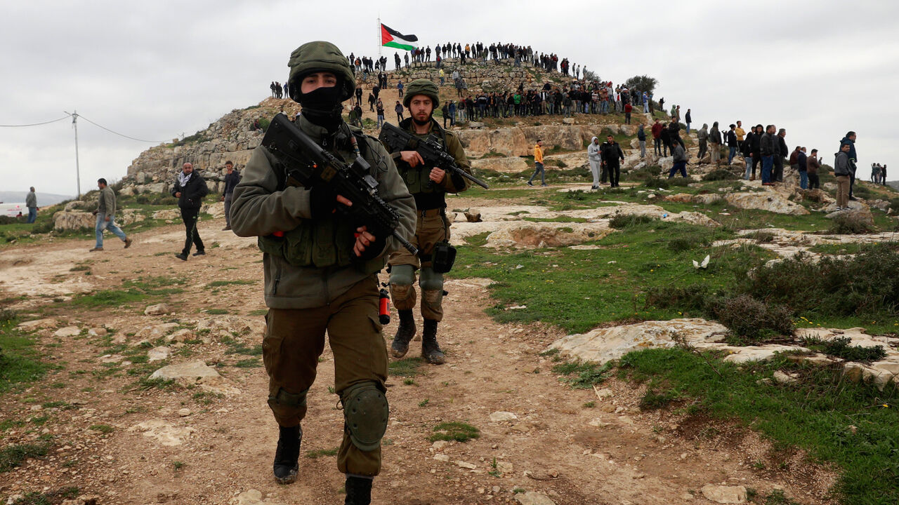 Israeli soldiers walk as Palestinian demonstrators gather on a hilltop during a protest against Israeli settlements in the town of Beita in the Israeli occupied West Bank, March 2, 2020. Picture taken March 2, 2020. REUTERS/Mohamad Torokman - RC2LDF9965R4