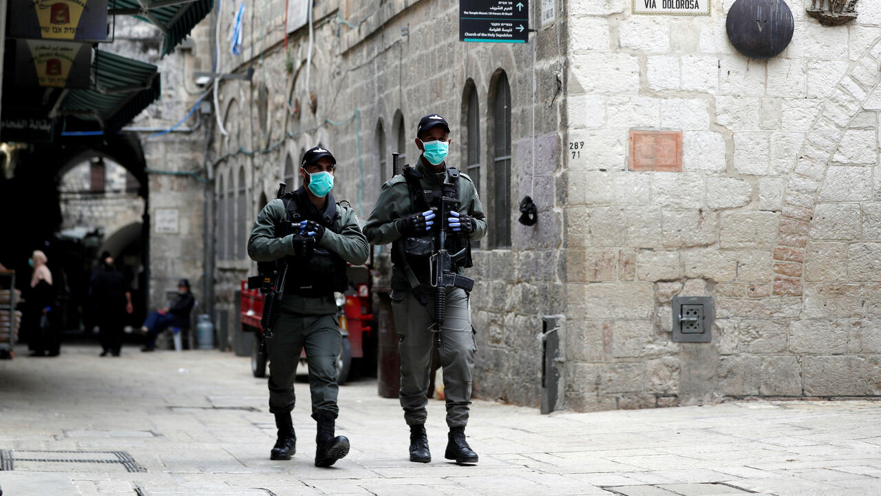Israeli police wearing masks walk near a bronze sculpture by Italian artist Alessandro Mutto at one of the Stations of the Cross along the Via Dolorosa, amid the coronavirus disease (COVID-19) outbreak in Jerusalem's Old City April 2, 2020. Picture taken April 2, 2020. REUTERS/Ammar Awad - RC2WYF955Z7O