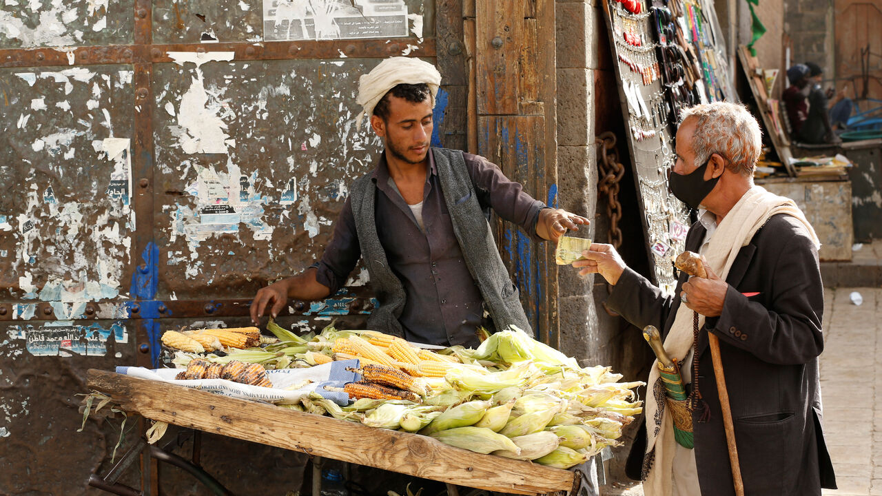 A man wearing a protective mask buys corn from a street vendor at a market amid novel coronavirus spread concerns in the old quarter of Sanaa, Yemen June 2, 2020. REUTERS/Khaled Abdullah - RC241H9PGGBD