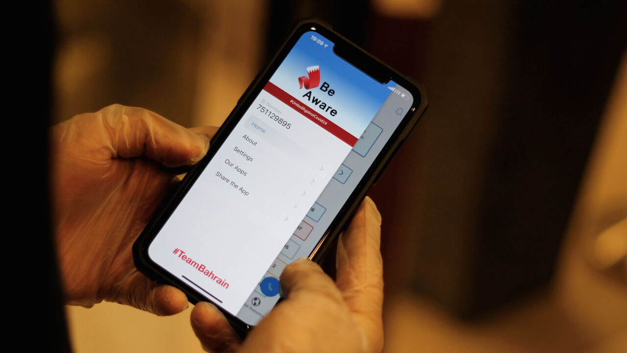 A man wearing protective gloves checks the app "Be Aware", launched by Bahrain's health authorities to contain the coronavirus disease (COVID-19) by spreading awareness and sharing updates on the situation, at a hotel in Manama, Bahrain, April 19, 2020. Picture taken April 19, 2020. REUTERS/Hamad I Mohammed - RC278G9BMSM2
