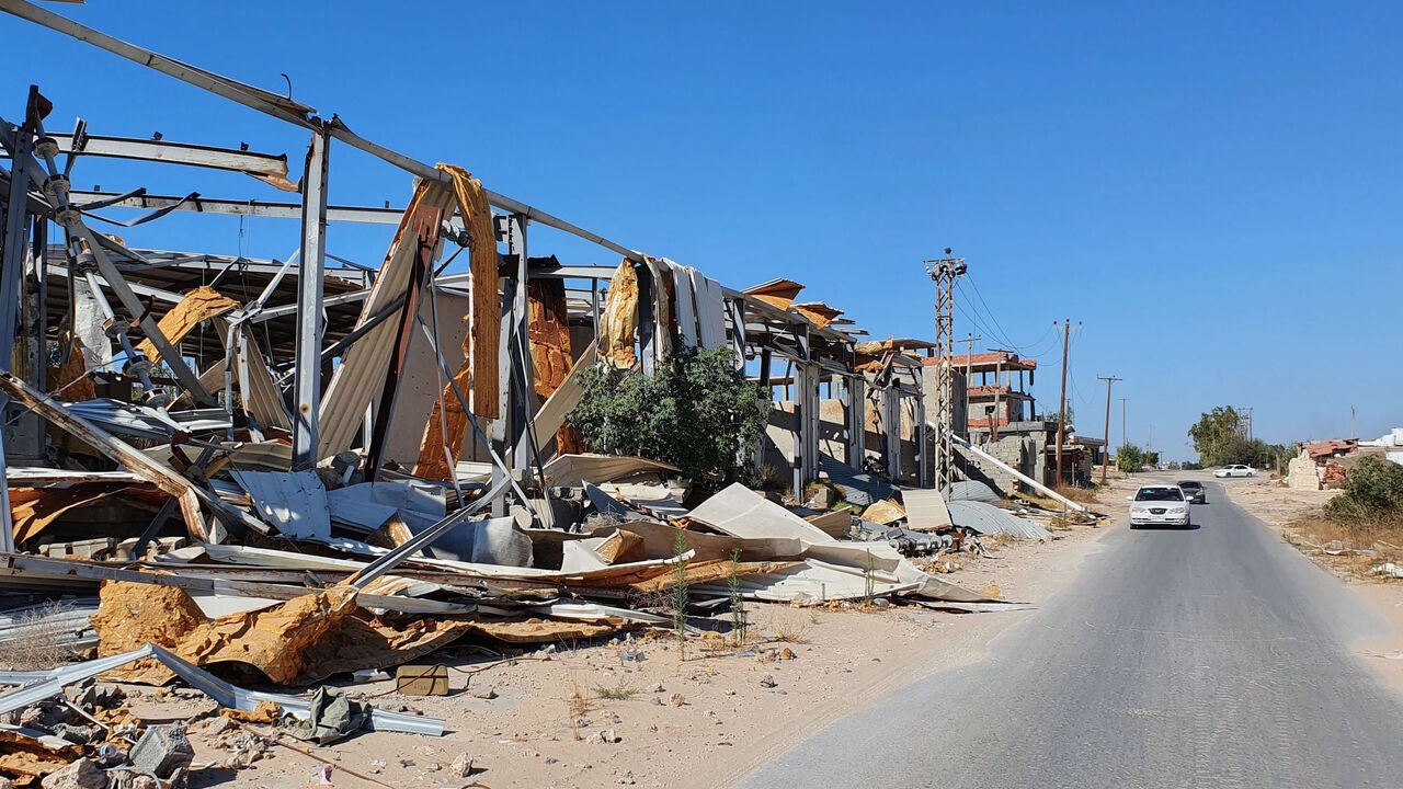 A car advances past a damaged facility in the Salaheddin district south of the Libyan capital Tripoli, on June 21, 2020, as some residents return to the area after it has been demined. - Since 2015, a power struggle has pitted the Tripoli-based Government of National Accord (GNA) against strongman Khalifa Haftar, who claims legitimacy from an eastern-based elected parliament, and had been trying unsuccessfully to seize the capital since April 2019, until a pro-GNA counter-offensive at the beginning of June 