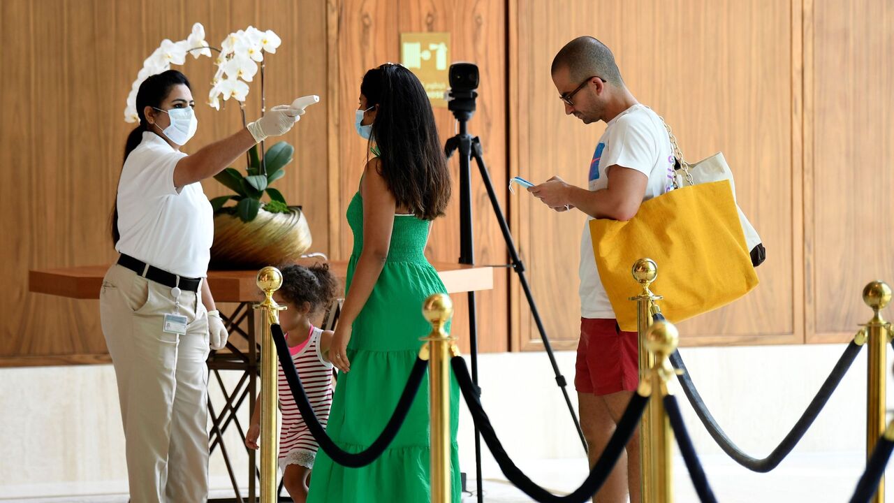A member of staff checks the temperature of a tourist at the Mandarin Oriental Jumeira on July 9, 2020 in the Gulf emirate of Dubai. - With a "welcome" passport sticker and coronavirus tests on arrival, Dubai reopened its doors to international visitors this week in the hope of reviving its tourism industry after a nearly four-month closure. (Photo by KARIM SAHIB / AFP) (Photo by KARIM SAHIB/AFP via Getty Images)