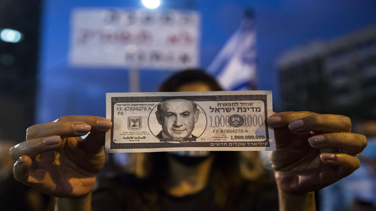 TEL AVIV, ISRAEL - JULY 11:  Israeli Protester holds a fake bill with  a photo of the Israeli Prime Minister Benjamin Netanyahu as she protests against the Government's economy response to the cororna virus crisis on July 11, 2020 in Tel Aviv, Israel. Following a rise in the cases of COVID-19, Israeli Prime Minister Benjamin Netanyahu has ordered many businesses to shut, causing people to protest about a perceived mishandling of the coronavirus pandemic and to call for the compensation promised by the gover