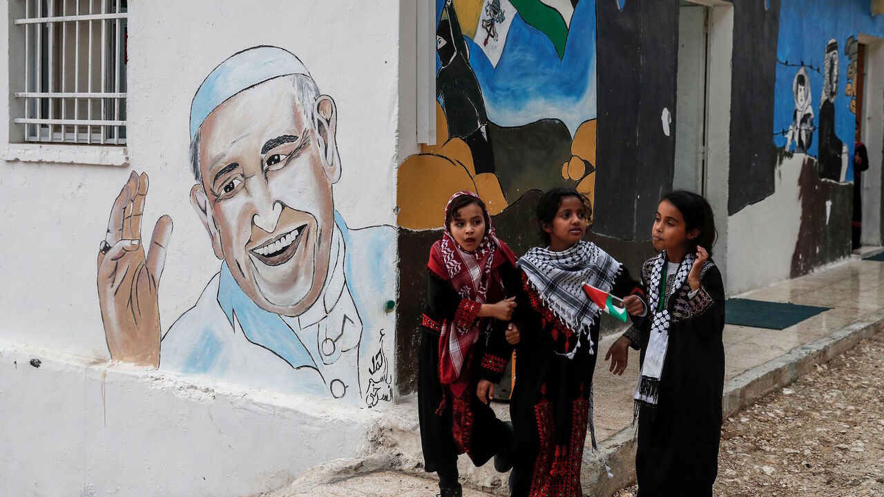 Palestinian girls walk past a mural of Pope Francis in the Jabal al-Baba Bedouin encampment, near the Israeli settlement of Maale Adumim in the occupied West Bank on the outskirts of Jerusalem, on November 23, 2017. / AFP PHOTO / AHMAD GHARABLI        (Photo credit should read AHMAD GHARABLI/AFP via Getty Images)