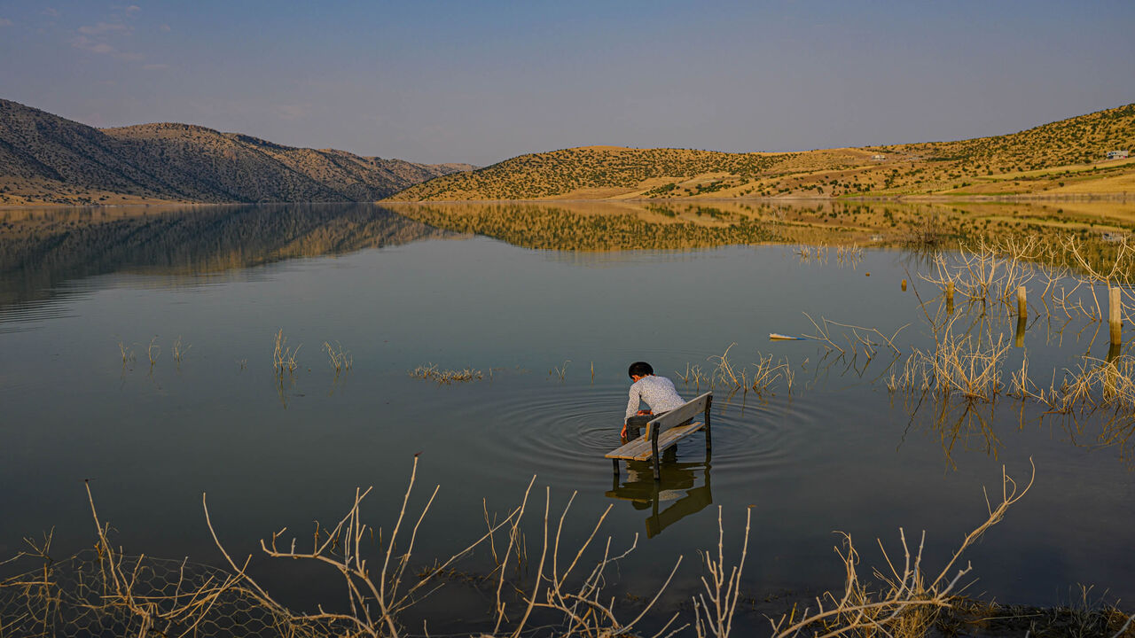 TOPSHOT - This picture taken on August 4, 2020, shows a boy sits on a school bench after his village and school were flooded by the Ilosu Dam separating the newly constructed Hasankeyf town from the remains of the ancient town of the same name and its archaeological sites which were flooded as part of the Ilõsu Dam project located along the Tigris River in the Batman Province in southeastern Turkey. - Despite years of protests by residents and activists, the town on the banks of the Tigris River disappeared