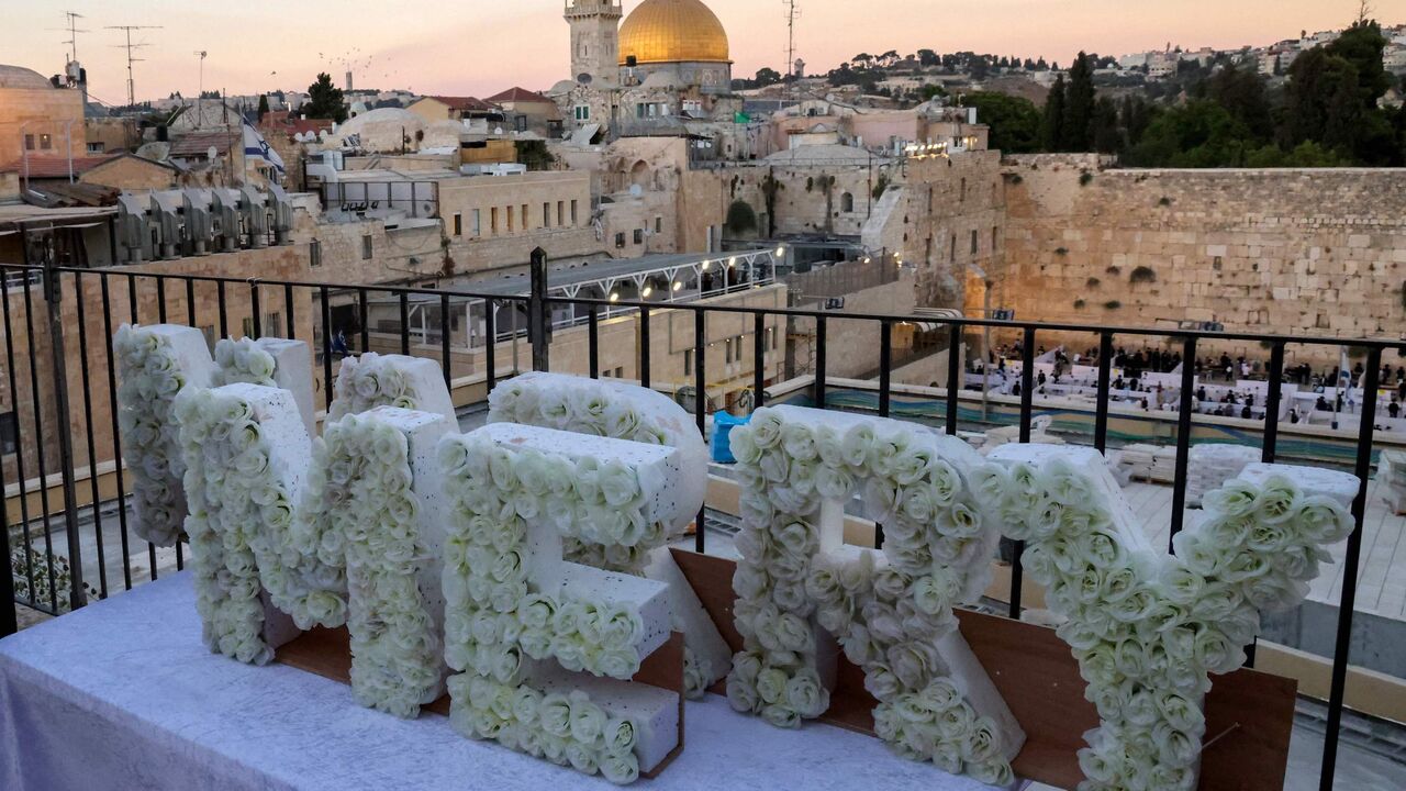 A Jewish couple stand together overlooking the Western wall and the Dome of the Rock mosque next to wedding floral decorations in Jerusalem's Old City on August 25, 2020. (Photo by Emmanuel DUNAND / AFP) (Photo by EMMANUEL DUNAND/AFP via Getty Images)