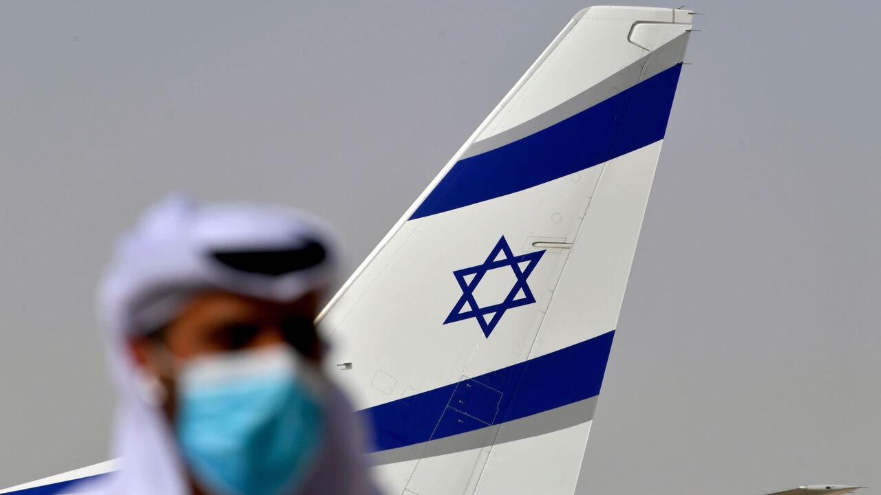 An Emirati official stands near an air-plane of El Al, which carried a US-Israeli delegation to the UAE following a normalisation accord, upon it's arrival at the Abu Dhabi airport in the first-ever commercial flight from Israel to the UAE, on August 31, 2020. - A US-Israeli delegation including White House advisor Jared Kushner took off on a historic first direct commercial flight from Tel Aviv to Abu Dhabi to mark the normalisation of ties between the Jewish state and the UAE. (Photo by Karim SAHIB / AFP)
