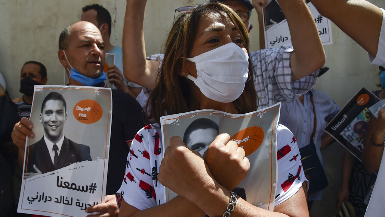 Algerian journalists gather in protest to demand the release of their colleague Khaled Drareni (poster), who was sentenced earlier this month to three years in jail for "inciting an unarmed gathering" and "endangering national unity", in the capital Algiers on August 24, 2020. - The Algerian justice system has in recent months increased the court cases and convictions against alleged Hirak militants, opposition politicians, journalists and social media users. (Photo by RYAD KRAMDI / AFP) (Photo by RYAD KRAM