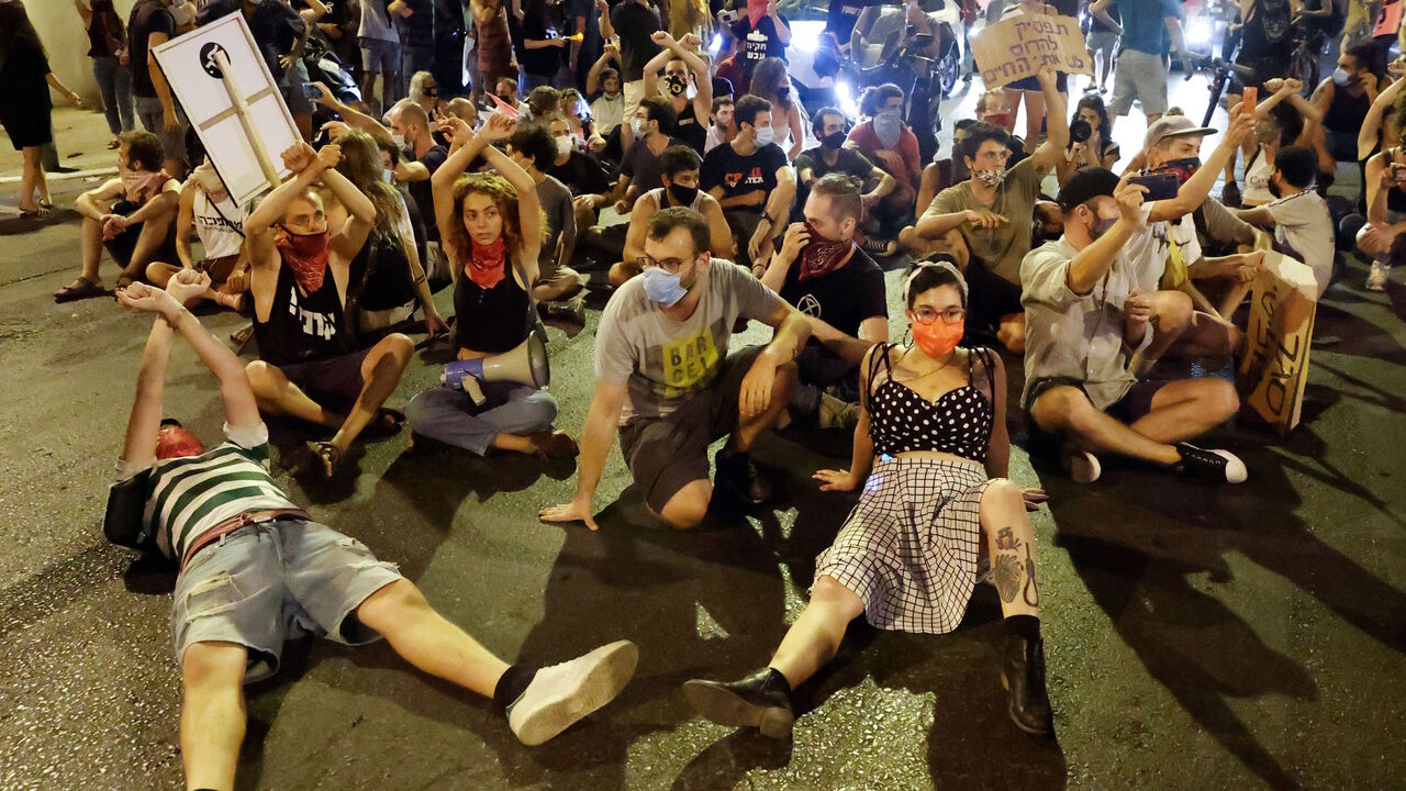 Israeli protesters sit on the ground during a demonstration against the Israeli prime minister and against the second nationwide lockdown imposed by the government in a bid to stem the increase of COVID-19 coronavirus cases, in the coastal city of Tel Aviv, on October 1, 2020. (Photo by JACK GUEZ / AFP) (Photo by JACK GUEZ/AFP via Getty Images)
