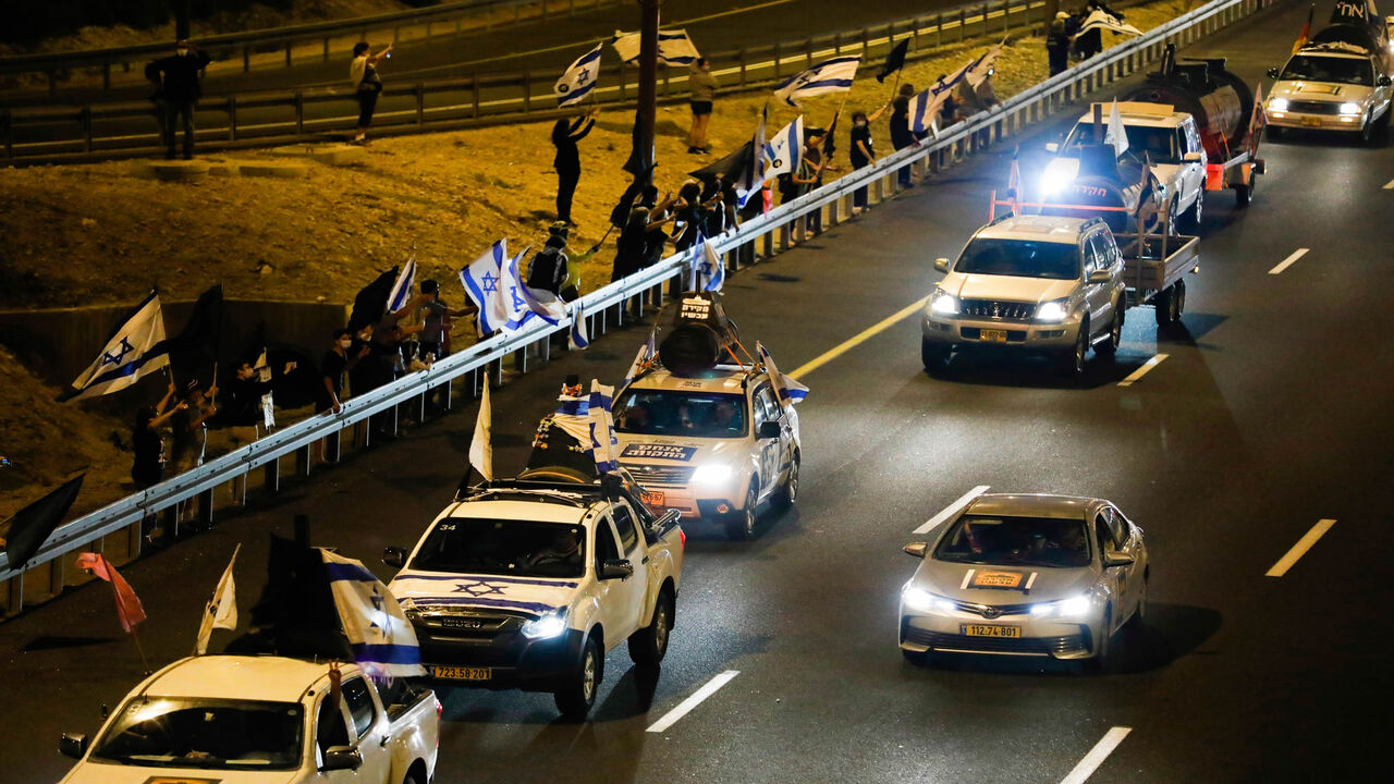 Drivers on the highway leading to Jerusalem wave Israeli national flags as they protest against the prime minister and against the second nationwide lockdown imposed by the government in a bid to stem the increase of COVID-19 infection cases, at the entrance of Jerusalem on October 14, 2020. (Photo by Ahmad GHARABLI / AFP) (Photo by AHMAD GHARABLI/AFP via Getty Images)