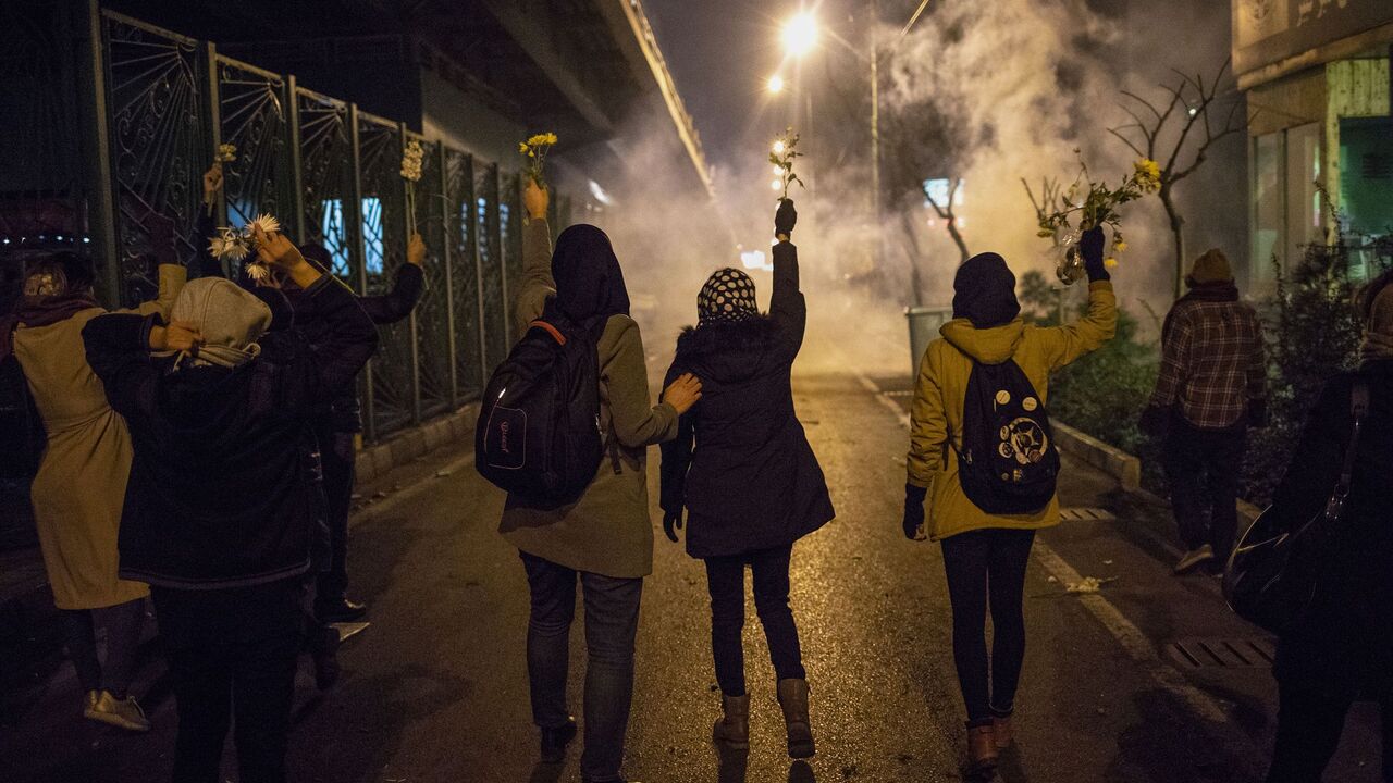 Iranian protesters hold flowers as riot police fire tear gas during a demonstration in front of Tehran's Amir Kabir University on January 11, 2020. - Demonstrations broke out for a second night in a row after Iran admitted to having shot down a Ukrainian passenger jet by mistake on January 8, killing all 176 people on board. (Photo by STR / AFP) (Photo by STR/AFP via Getty Images)