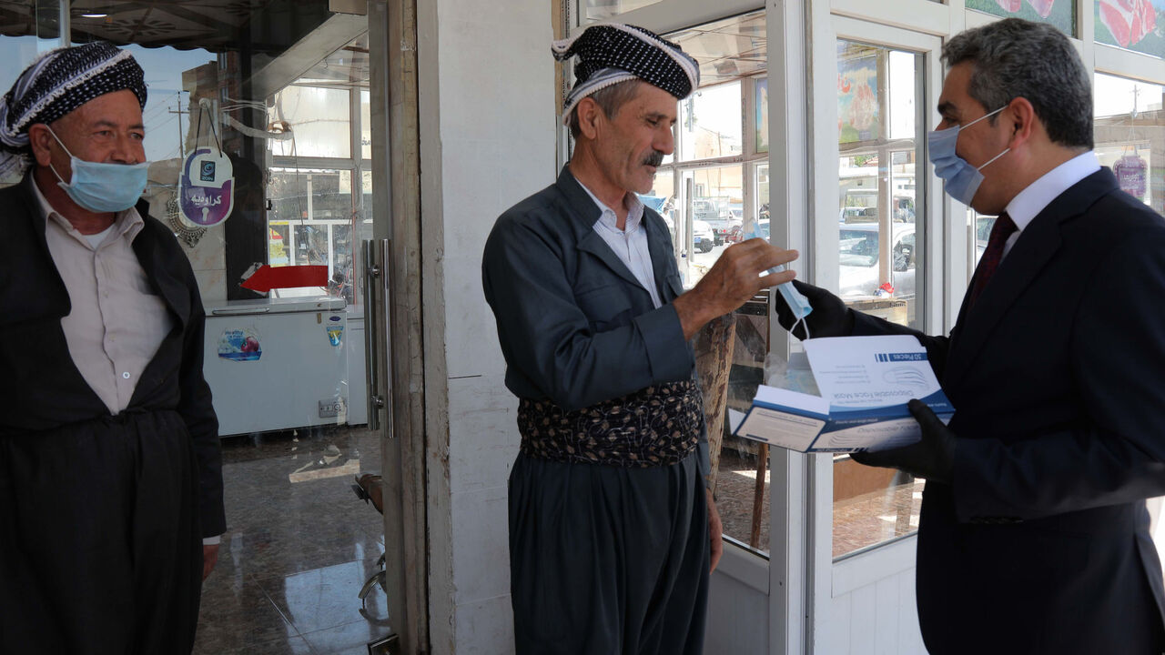 Firsat Sofi (R), the governor of Arbil, gives mask to people to protect themselves against the coronavirus COVID-19, on June 4, 2020 in Arbil, the capital of the autonomous Kurdish region of northern Iraq. (Photo by SAFIN HAMED / AFP) (Photo by SAFIN HAMED/AFP via Getty Images)