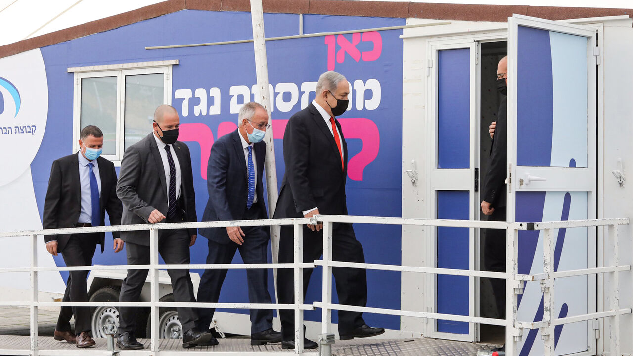 Israeli Prime Minister Benjamin Netanyahu (R) and Health Minister Yuli Edelstein (L) arrive at the Maccabi Healthcare Services vaccine complex, handling the COVID-19 coronavirus vaccine, in Israel's Mediterranean coastal city of Tel Aviv on December 13, 2020. (Photo by Marc Israel SELLEM / POOL / AFP) (Photo by MARC ISRAEL SELLEM/POOL/AFP via Getty Images)