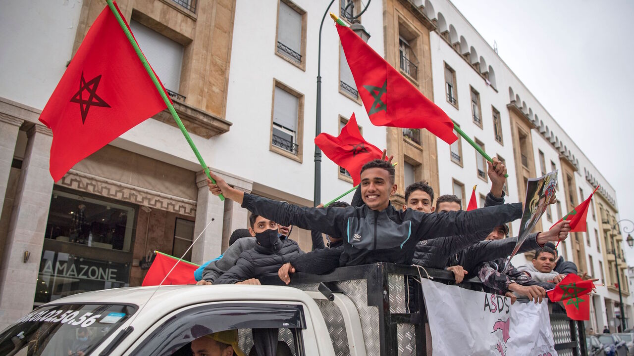 Moroccans celebrate in front of the parliament building in Rabat on December 13, 2020, after the US adopted a new official map of Morocco that includes the disputed territory of Western Sahara. - Western Sahara is a disputed and divided former Spanish colony, mostly under Morocco's control, where tensions with the pro-independence Polisario Front have simmered since the 1970s. Morocco became the fourth Arab state this year, after the United Arab Emirates, Bahrain and Sudan, to announce it had agreed to norm