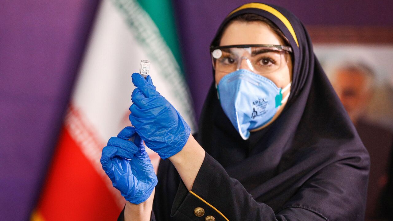 A health worker prepares an injection for a woman during the first trial phase of a locally-made Iranian vaccine for COVID-19 coronavirus disease in Iran's capital Tehran on December 29, 2020. (Photo by - / AFP) (Photo by -/AFP via Getty Images)