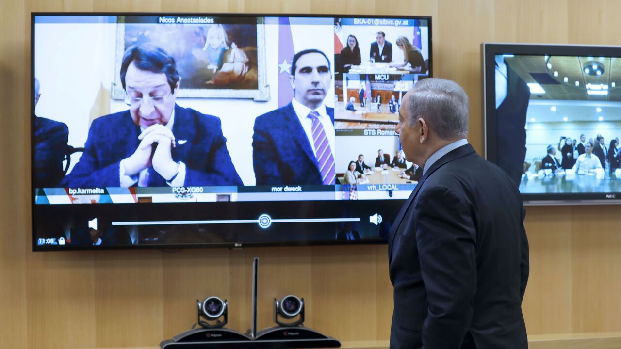 Israeli Prime Minister Benjamin Netayahu stands in front of a screen showing the president of Cyprus, Nicos Anastasiades, during a video conference with European leaders in order to discuss challenges and cooperation between various countries in dealing with COVID-19 coronavirus, at the Foreign Ministry in Jerusalem on March 9, 2020. (Photo by MENAHEM KAHANA / AFP) (Photo by MENAHEM KAHANA/AFP via Getty Images)