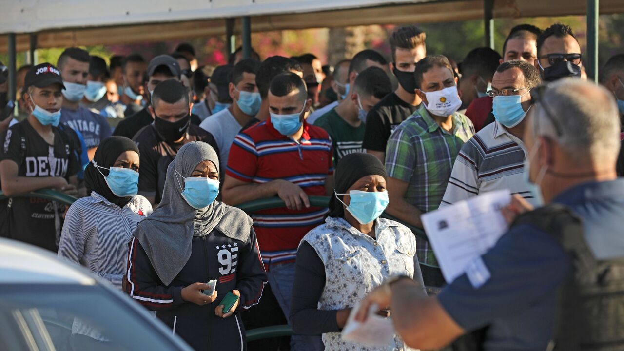 Palestinian workers wearing masks against Covid-19 lineup for a security check at the entrance to Israel's Mishor Adumim industrial zone nearby the Maale Adumim settlement in the West Bank east of Jerusalem, on July 1, 2020. - The government of Israeli Prime Minister Benjamin Netanyahu has said it could begin the process to annex Jewish settlements in the West Bank as well as the strategic Jordan Valley from today. The plan -- endorsed by Washington -- would see the creation of a Palestinian state, but on r
