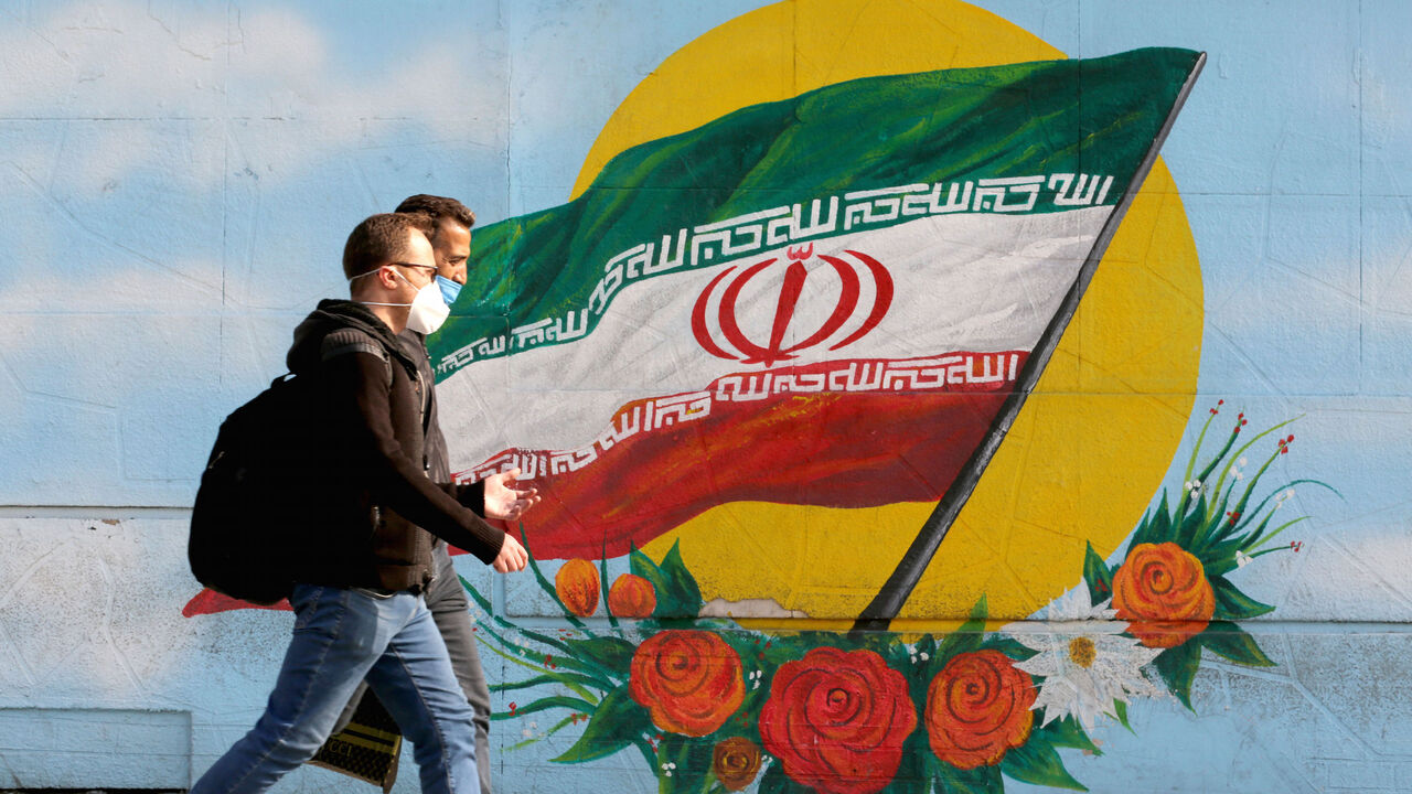 Men walk while wearing face masks amid the COVID-19 pandemic in the Iranian capital Tehran, on November 30, 2020. (Photo by ATTA KENARE / AFP) (Photo by ATTA KENARE/AFP via Getty Images)