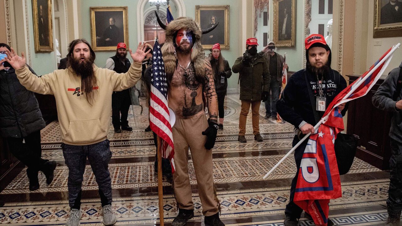 Supporters of US President Donald Trump, including Jake Angeli (C), a QAnon supporter known for his painted face and horned hat, enter the US Capitol on January 6, 2021, in Washington, DC. - Demonstrators breeched security and entered the Capitol as Congress debated the a 2020 presidential election Electoral Vote Certification. (Photo by SAUL LOEB / AFP) (Photo by SAUL LOEB/AFP via Getty Images)