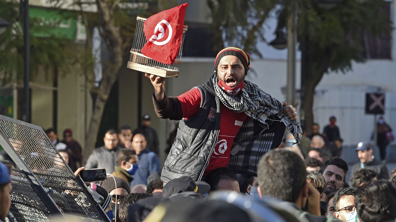 A Tunisian protester lifts a flag-clad birdcage during an anti-government demonstration on the Habib Bourguiba avenue in the capital Tunis, on January 19, 2021. - Tunisia braced for further protests after hundreds were arrested in four nights of street clashes between riot police and disaffected youths in cities across the North African country. (Photo by FETHI BELAID / AFP) (Photo by FETHI BELAID/AFP via Getty Images)
