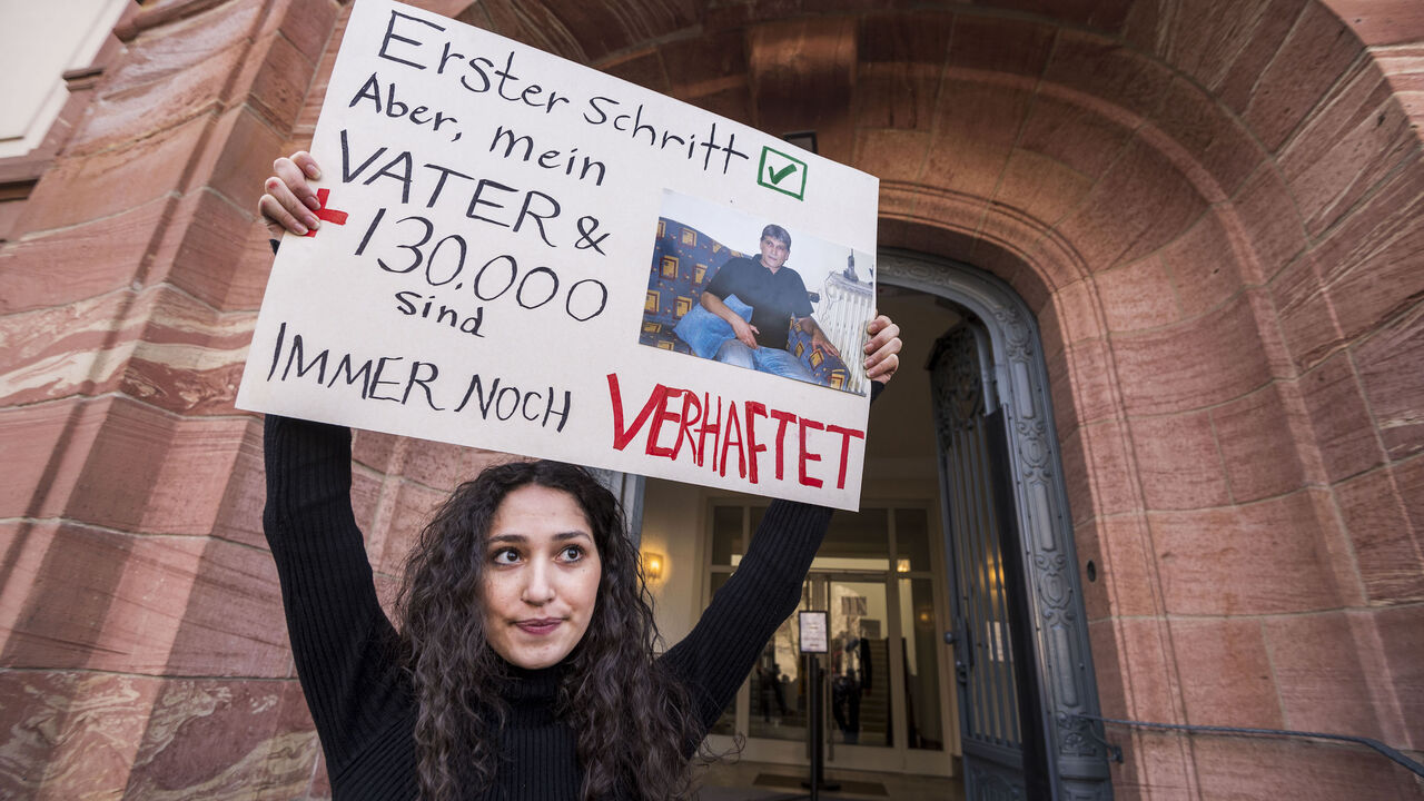 Sedra Alshehabi stands with a placard with the picture of her father Ali and a text reading 'First step but my father and 130000 are still in jail' after the verdict in the trail of Syrian defendant Eyad al-Gharib, accused of crimes against humanity in the first trial of its kind to emerge from the Syrian conflict on February 24, 2021 in Koblenz, western Germany. - Eyad al-Gharib, 44, former Syrian intelligence service agent was sentenced to four and a half years in jail for complicity in crimes against hum