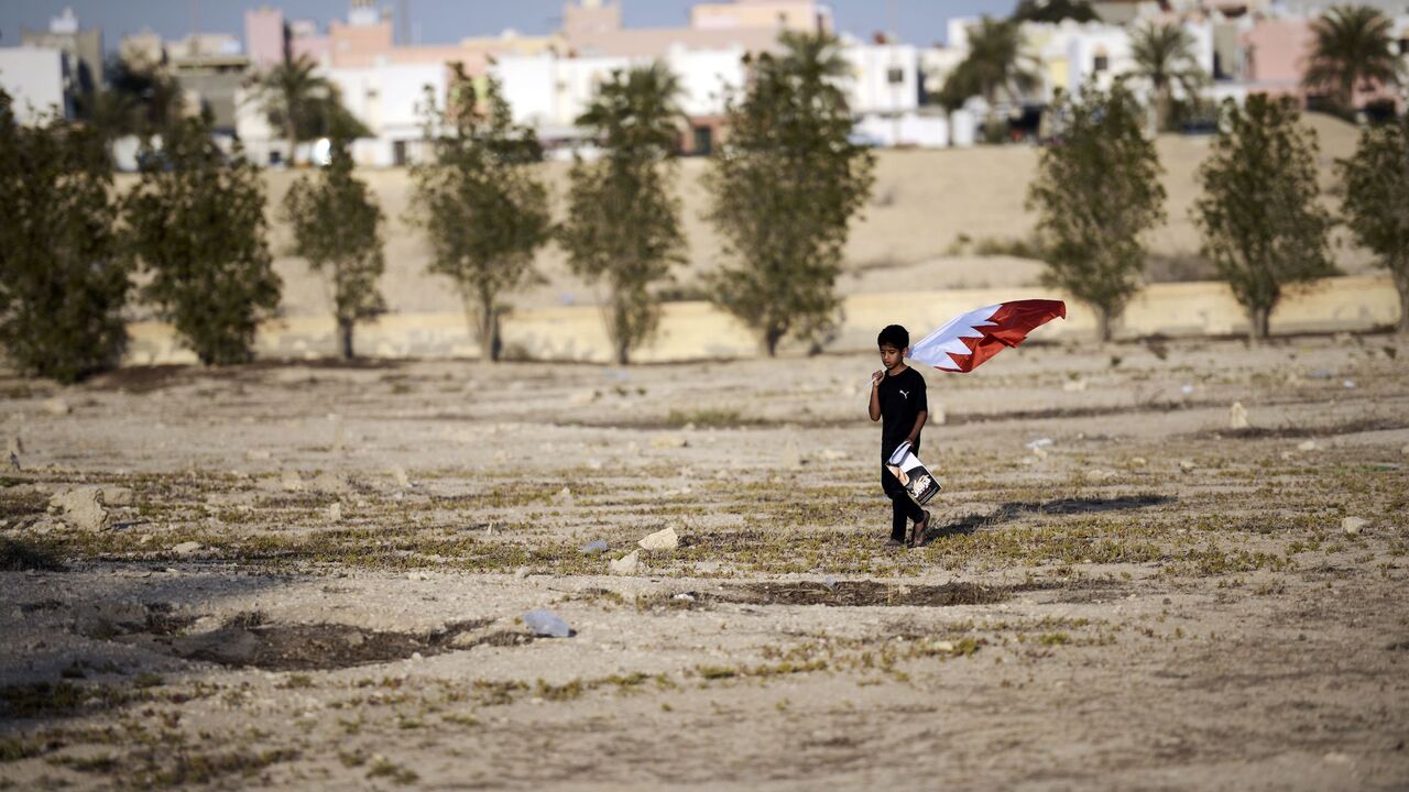 A Bahraini boy carries his national flag during the funeral of Ali Abdulghani, 17, whose family says died of injuries suffered in a police chase, in the Shiite village of Shahrakkan, south of Manama on April 5, 2016.  / AFP / MOHAMMED AL-SHAIKH        (Photo credit should read MOHAMMED AL-SHAIKH/AFP via Getty Images)