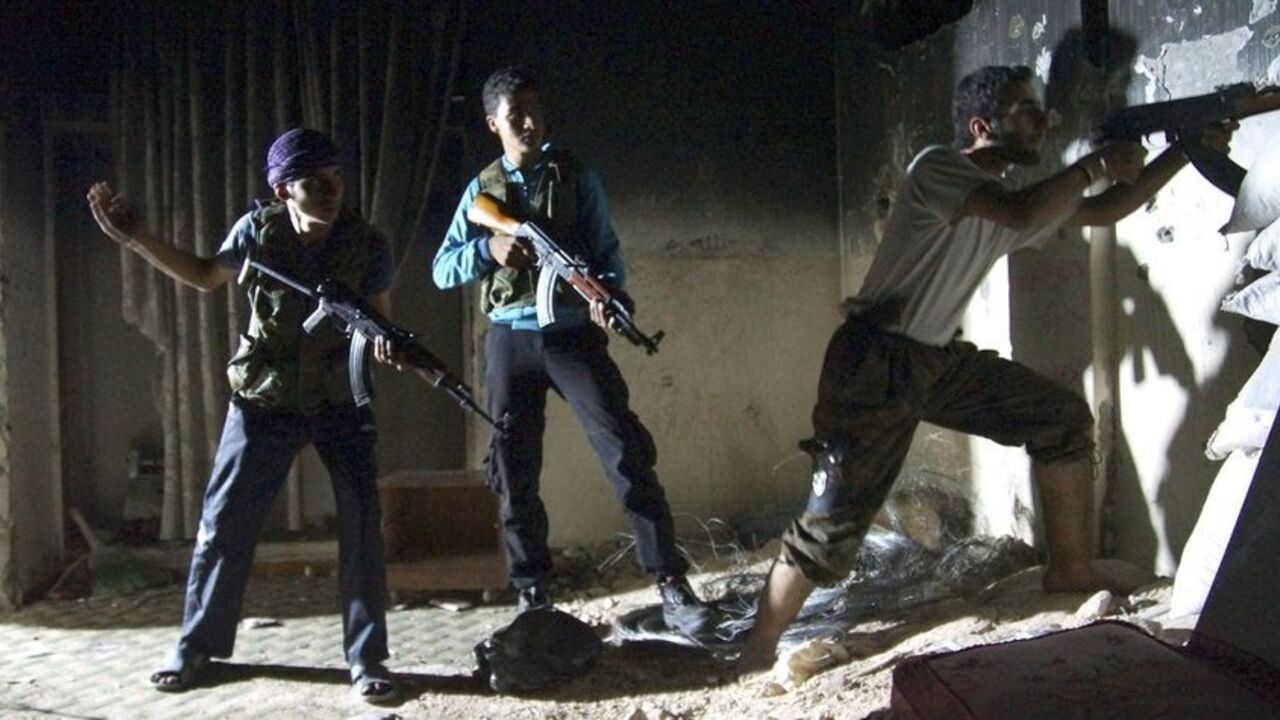 A member of the Free Syrian Army aims his weapon as fellow fighters stand behind him in Deir al-Zor July 22, 2013. Picture taken July 22, 2013. REUTERS/Khalil Ashawi (SYRIA - Tags: CONFLICT MILITARY CIVIL UNREST TPX IMAGES OF THE DAY) - RTX11VPZ