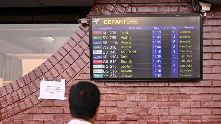 A man looks at a screen displaying the flight schedule at the Hazrat Shahjalal International Airport in Dhaka, on Oct. 12, 2026, as Saudi Arabia-bound flights remain canceled a day after a Houthi strike at Riyadh's international airport
