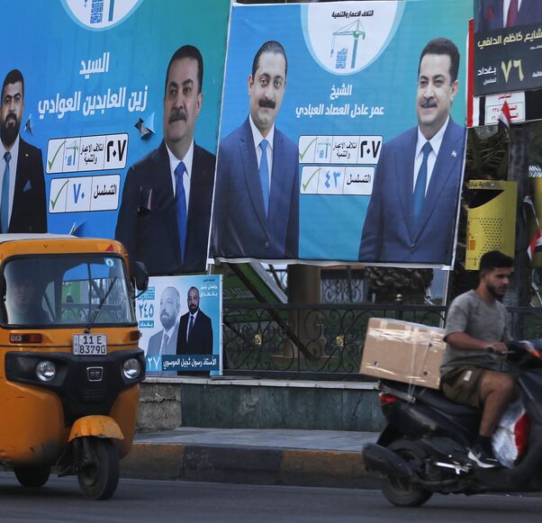 People drive past election billboards in Baghdad, Oct. 14, 2025. 