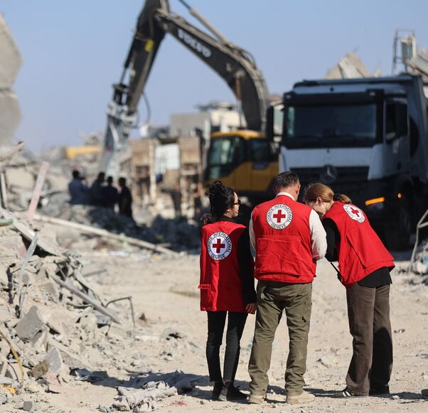 Members of the Red Cross stand amid the rubble of destroyed buildings as heavy machinery operates in the al-Tuffah neighborhood of Gaza City on Oct. 27, 2025. 