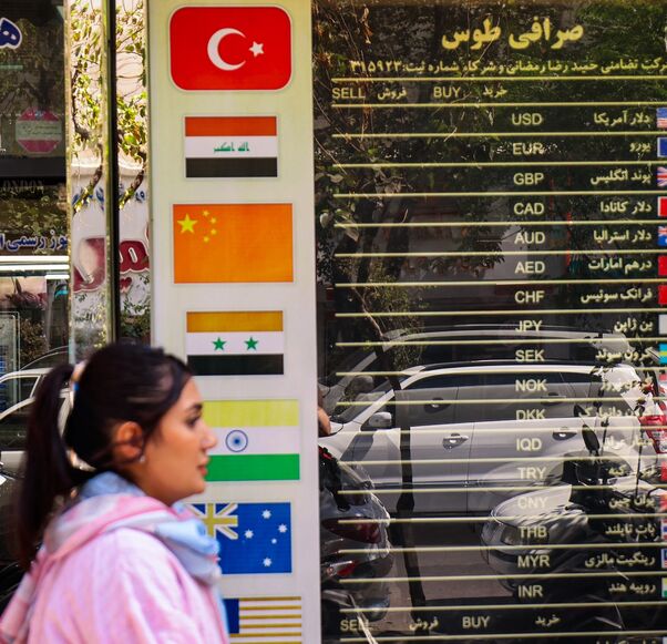 A woman walks past a currency exchange office in Tehran on Sept. 28, 2025, as Iranians feel economic strain deepen, with prices soaring and the rial sinking to new lows. 