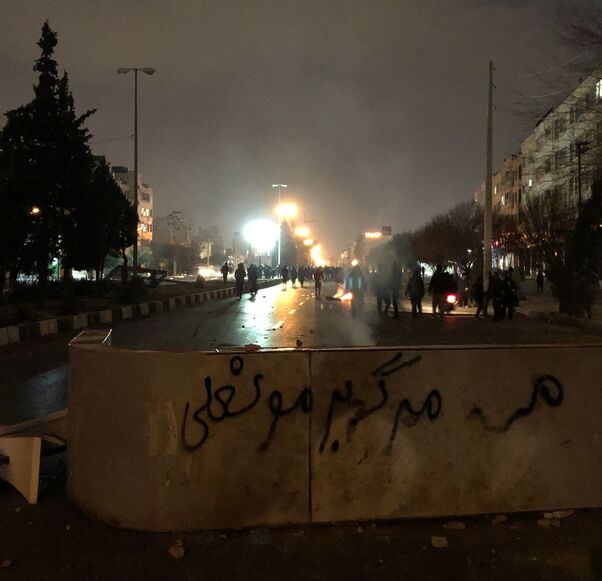 Iranian protesters block a street as a slogan against Iran's supreme leader is spray-painted nearby during a demonstration in Shiraz, Iran, on Jan. 10, 2026. 