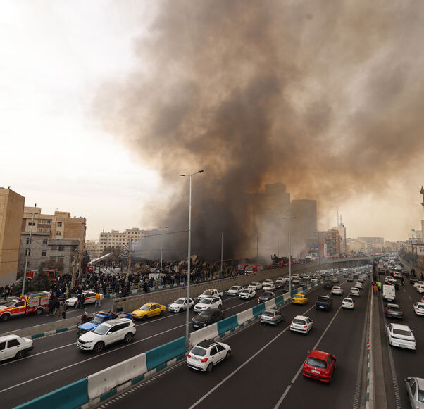 Motorists drive past as firefighters battle a fire that broke out in Jannat Bazaar, west of Tehran on Feb. 3, 2026. 
