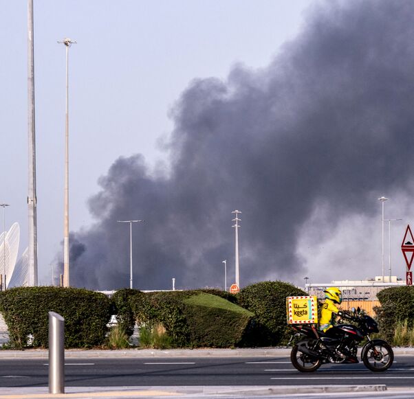 A food delivery bike drive close to a plume of smoke rising from the Zayed Port following a reported Iranian strike in Abu Dhabi on March 1, 2026. Iran's retaliatory missile and drone campaign in the Gulf has killed three people and wounded 58 in the United Arab Emirates since it began, Emirati authorities said on March 1, the day after the US and Israel launched a nationwaide attack on Iran killing its supreme leader. (Photo by Ryan Lim / AFP via Getty Images)