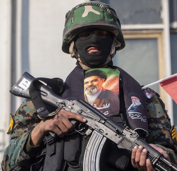 A security forces member with a picture of Iran's new supreme leader, Ayatollah Mojtaba Khamenei, watches over demonstrators as they gather for a rally in support of the new supreme leader at Enghelab Square on March 9, 2026 in Tehran, Iran. 