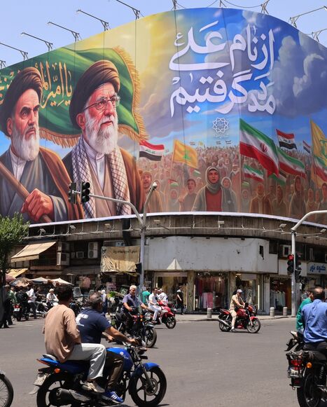 People ride motorcycles past a large billboard showing portraits of Iran's late supreme leader, Ayatollah Ruhollah Khomeini (L), and slain supreme leader Ayatollah Ali Khamenei (R) in central Tehran on June 8, 2026. 