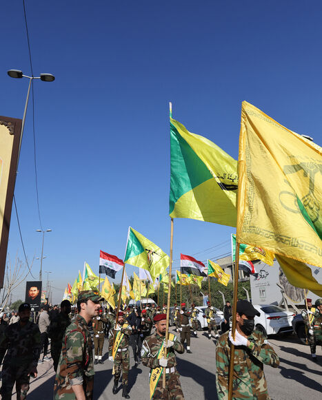 Fighters lift flags of Iraq and paramilitary groups, including al-Nujaba and Kataib Hezbollah, during a funeral in Baghdad for five militants killed a day earlier in a US strike in northern Iraq, on Dec. 4, 2023. 