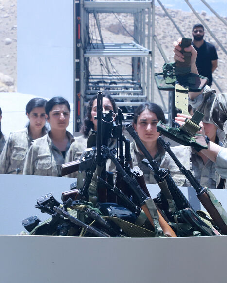 Fighters with the Kurdistan Workers' Party (PKK) line up to put their weapons into a pit during a ceremony in Sulaimaniyah, in Iraq's autonomous Kurdistan region, on July 11, 2025. 