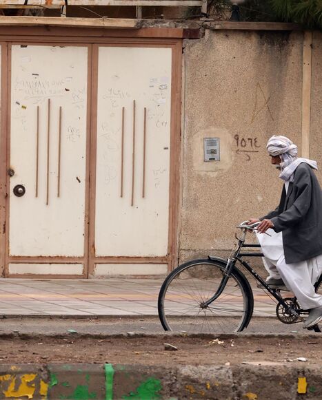 A Baluch Iranian man rides a bicycle
