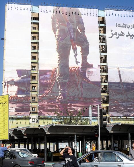 A woman crosses a street near a giant billboard erected on the facade of a building depicting a member of Iran's Islamic Revolutionary Guards Corps placing his foot on a US sea drone, reportedly seized by Iran in the Strait of Hormuz, in Vanak Square in Tehran, on Sept. 24, 2026.