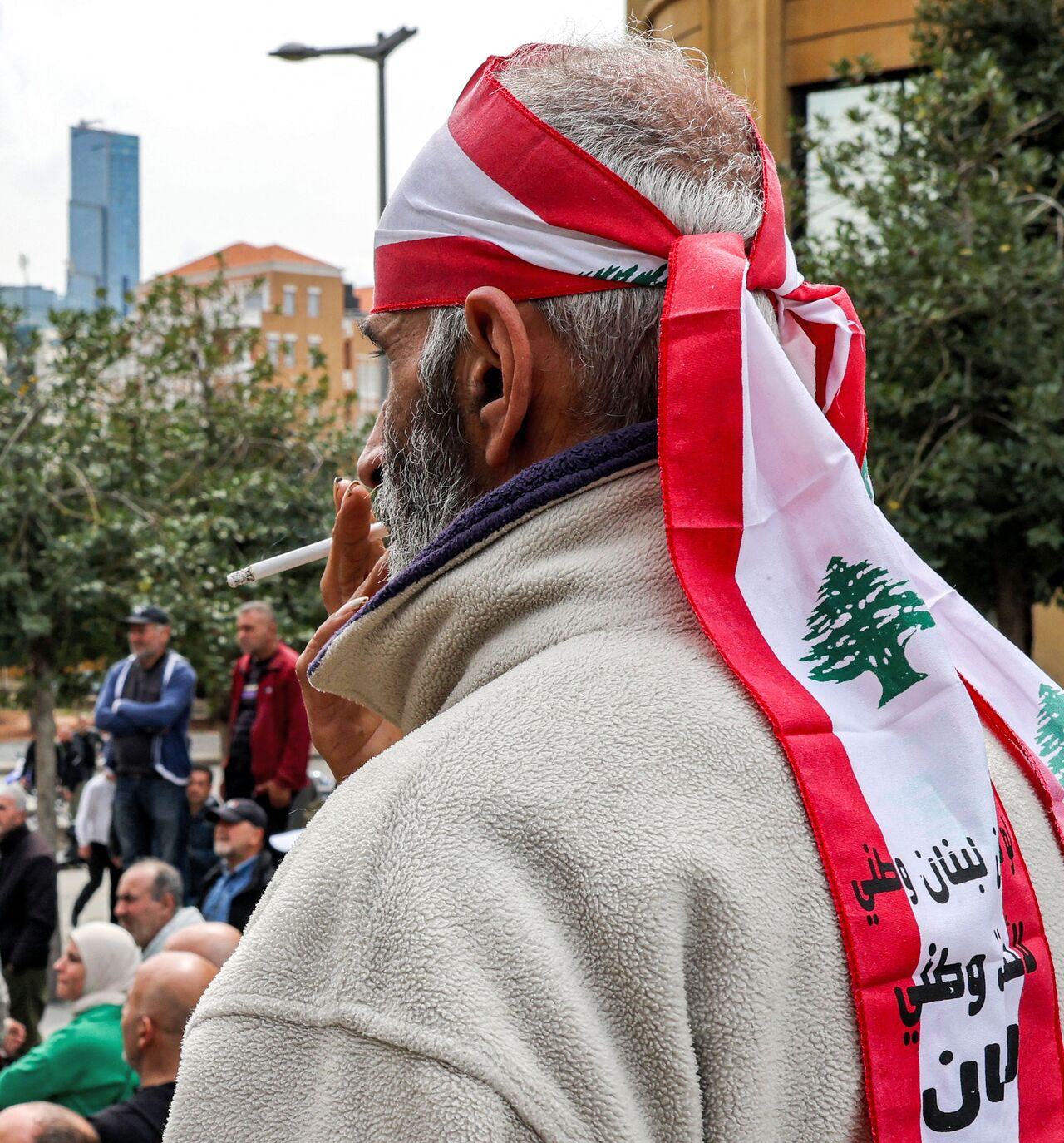 A demonstrator wearing a bandana in the colours of the Lebanese flag smokes a cigarette as retired Lebanese army and security forces veterans gather to protest outside the government palace headquarters in the centre of Beirut on March 22, 2023, demanding inflation-adjustments to their pensions. (Photo by Joseph EID / AFP) (Photo by JOSEPH EID/AFP via Getty Images)