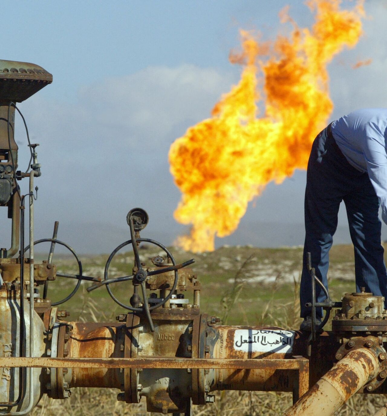 A worker turns a valve at the Shirawa oil field, where oil was first pumped in Iraq in 1927, outside the northern city of Kirkuk, Jan. 19, 2004.